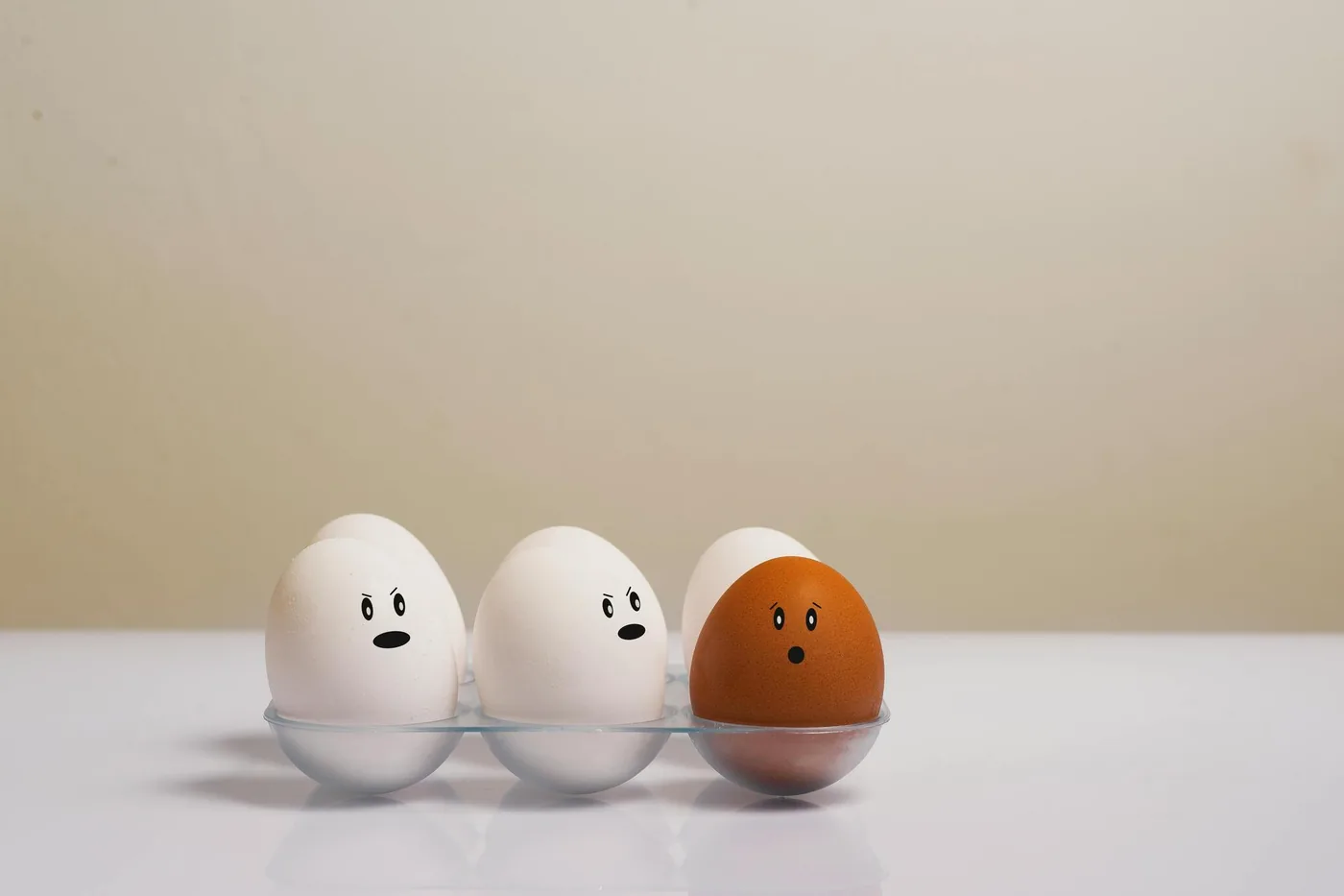 Eggs with different drawn-on facial expressions arranged in a tray